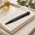 Black Stone Facial Massage Wand beside towels and facial oil